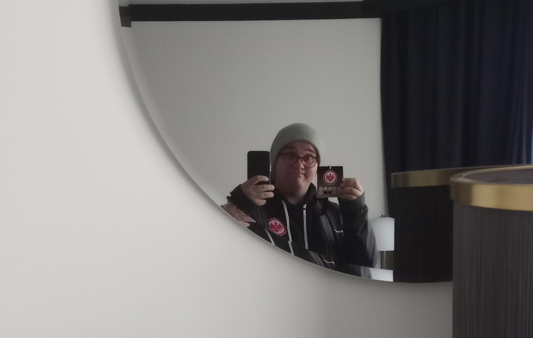 Spiegelselfie in einem Prager Hotelzimmer, ich trage Dienstkleidung und halte meine Akkreditierung hoch